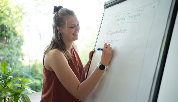 Studentin schreibt an einem Flipchart im Freien